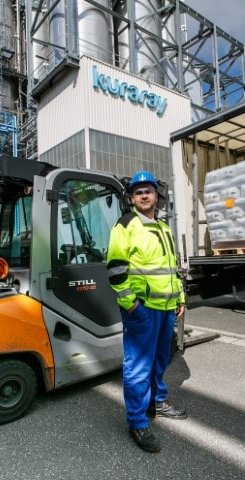 Kuraray Europe GmbH employee wearing blue work pants, yellow jacket and blue safety helmet.